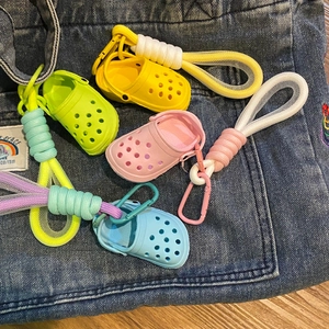 Close-up of four colorful mini clog shoe keychains with woven lanyards on denim
