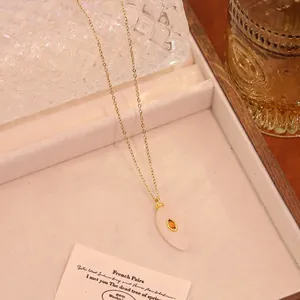 Détail du collier en or avec pierre blanche ovale et gemme orange en boîte