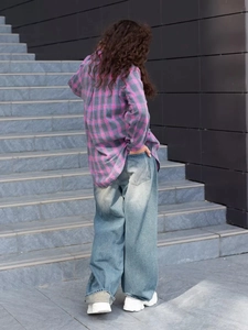 Rear view of a pink and grey plaid patchwork shirt with light blue wide-leg jeans