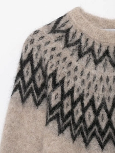Close-up of beige knit sweater showing soft alpaca texture and black geometric patterns