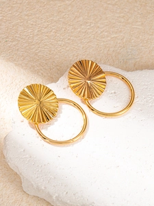 Detail of gold geometric earrings with textured disc and hoop on stone display