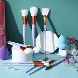 Unicorn makeup brush set with purple spiral handles and rose gold ferrule on white props