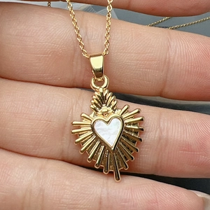 Golden heart pendant necklace featuring natural shell inlay and sunburst ray design