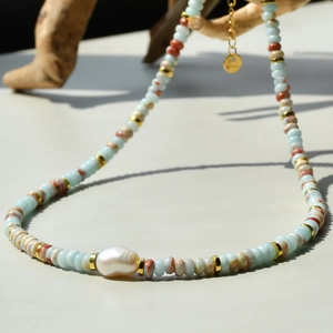 Detail of freshwater pearl necklace with light blue beads and golden accents