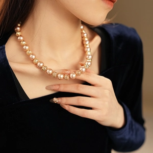 Detail of hollow metal beads and pearls on an elegant gold-toned necklace for women