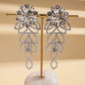 Macro detail of silver floral dangle earrings with crystals on a golden stand