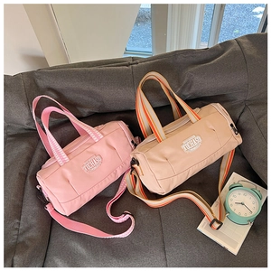 Pink and beige cylinder duffel bags with adjustable straps and TOCHASO logo on top