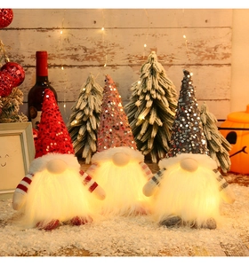 Close-up of three glowing Christmas gnomes with colorful sequin hats and warm light