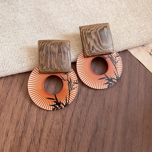 Macro view of square wood block and round bamboo pattern pendant on drop earrings
