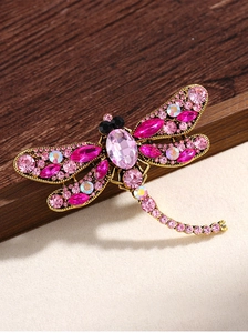 Detail of vintage dragonfly brooch with pink crystals and antique gold metal setting