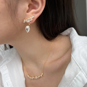 Detail of elegant gold olive branch necklace and teardrop earrings set with cubic zirconia