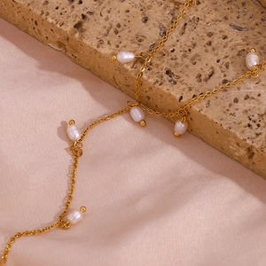 Détail macro du collier en Y doré avec perles d'eau douce naturelles sur tissu de soie