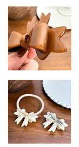 Detail showing acetate brown and white bow hair clips and scrunchie on a wooden table