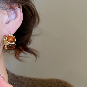 Detail of amber resin stud earrings with gold base showing square stones and earring back