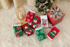 Details von festlichen Korallenfleece-Weihnachtssocken auf einem weichen weißen Teppich