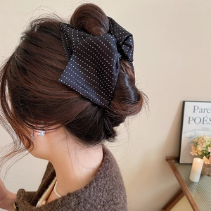 Polka dot bow hair claw clip styled on a model's elegant French bun updo hair