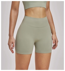 Detailed texture of seamless high-waisted sage green yoga shorts on model for fitness