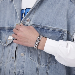 Detail of silver stainless steel Cuban chain bracelet with Greek key pattern on wrist