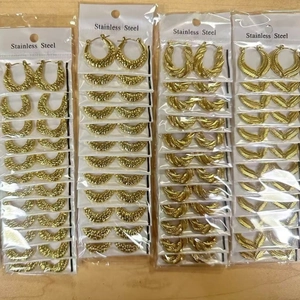 Macro detail of gold stainless steel hoop earrings with various textured wave patterns