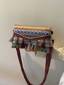 Detailed view of bohemian woven crossbody bag with colorful tassels and ethnic strap