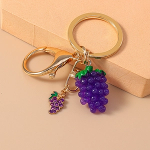 Macro detail of purple grape keychain with golden metal ring on beige textured cubes