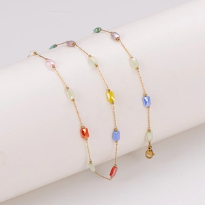Colorful faceted rectangle bead necklace with a gold chain on a white cylinder stand