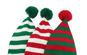 Close-up of festive striped Christmas knit beanies with fluffy pom poms in red and green