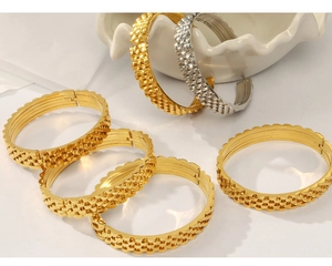 Detail of gold and silver steel bracelets showing industrial textured gear patterns