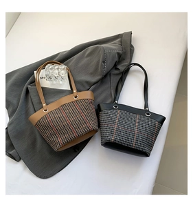 Detailed texture of retro plaid tote bag with leather handle on grey blazer