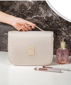 Close-up of beige hanging toiletry bag featuring a sturdy handle and travel logo tag