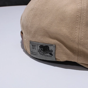 Makroaufnahme der Canvas-Stoffstruktur und des Logo-Aufnähers auf beige Schirmmütze