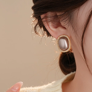 Detailed view of a model wearing vintage gold-framed oval earrings with zircon accents