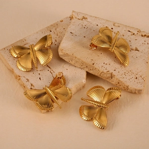 Elegant 18K gold stainless steel dragonfly earrings displayed on a textured stone plate