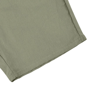 Detail of light green linen shorts featuring reinforced double-needle stitching on hem