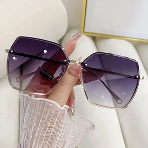 Detail shot of purple gradient lenses and gold metal frames on oversized square sunglasses