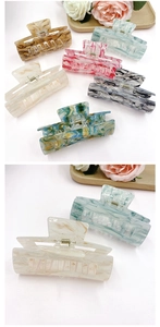 Detail of multi-color marble acrylic hair claws on a wooden tray with a rose decoration