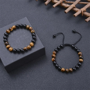 Detail von 8mm Tigerauge und Obsidian Perlenarmbändern auf einer schwarzen Schmuckschatulle