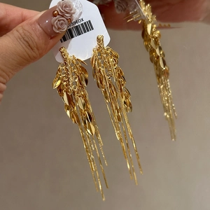 Dettaglio macro di orecchini a foglia dorata con lunghe catene a frangia