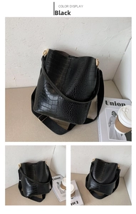 Detail of black crocodile pattern bucket bag with wide fabric strap and gold hardware