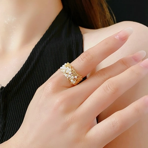Primo piano di un elegante anello placcato oro con perle bianche indossato sul dito