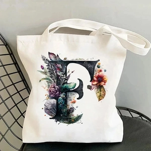 Detail of canvas tote bag with floral letter F print placed on a black mesh chair