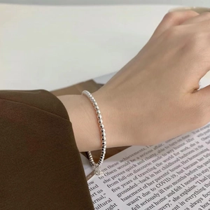 Macro detail of minimalist 925 sterling silver bead bracelet on a model's wrist