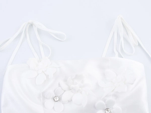 Detail of white top with 3D floral applique, rhinestone accents, and bow shoulder straps