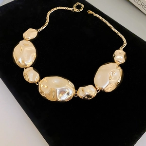 Macro view of gold-tone necklace featuring seven polished irregular links on black velvet