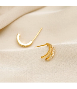 Macro shot of gold double-layer C-shape stud earrings with shimmering cubic zirconia