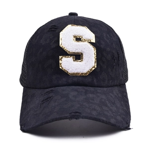 Detail of black baseball cap with leopard print canvas and white letter S patch