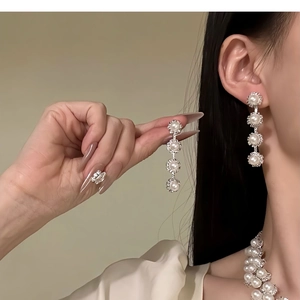 Close-up of elegant pearl drop earrings and necklace set with silver crystal accents