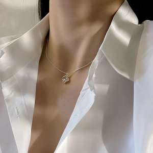 Close-up of minimalist silver irregular geometric pendant on a delicate chain necklace