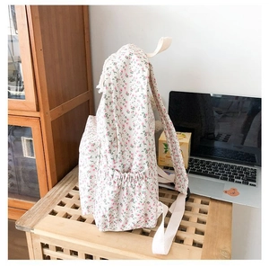 Close-up of floral school backpack with side elastic pocket on wooden stool
