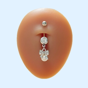 Détail du piercing de nombril argenté avec nœud en cristal et perle blanche pendante